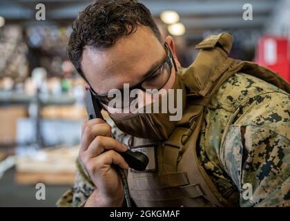 PAZIFIK (15. April 2021) U.S. Marine Corps Sgt. Kevin Schweitzer, ein nicht beauftragter Beamter für psychologische Operationen bei der 11. Marine Expeditionary Unit (MEU), führt vor einer simulierten Mission zur Verstärkung der Botschaft am 15. April eine Funktionsprüfung an einem Lautsprecher der nächsten Generation durch, der an Bord des amphibischen Sturmschiffes USS Essex (LHD 2) demontiert wurde. Marineinfanteristen und Segler der 11. MEU und der Essex Amphibious Ready Group (ARG) sind im Gange, um vor der Küste Südkaliforniens ein integriertes Training durchzuführen. Stockfoto