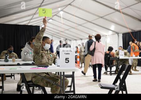 US Air Force Staff Sgt. Jasmine French, ein gebürtiger gebürtiger aus Los Angeles, Kalifornien, und ein Gesundheitsdienstadministrator, der der 335. Air Expeditionary Group zugewiesen wurde, signalisiert einem Gemeindemitglied einen verfügbaren Sitz im föderal geführten Pilotgemeinschaftsimpfungszentrum in Greenbelt, Maryland, 17. April 2021. Das U.S. Northern Command setzt sich über die U.S. Army North weiterhin dafür ein, die Federal Emergency Management Agency im Rahmen der Reaktion der gesamten Regierung auf COVID-19 weiterhin flexibel und flexibel zu unterstützen. Stockfoto