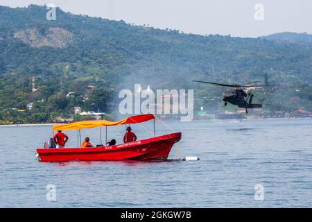 Eine US-Army-Besatzung führt während des Überwassertrainings in Trujillo Bay, Honduras, am 18. April 2021 eine Helocast-Trainingsübung in einem HH-60L Blackhawk-Hubschrauber durch, der dem 1. Bataillon, dem 228. Luftfahrtregiment, Joint Task Force-Bravo, Soto Cano Air Base, Honduras, zugewiesen wurde. Die Schulung bereitete die Dienstmitglieder darauf vor, auf Notfälle im Überwasser-Flug reagieren zu können und die Sicherheit der Besatzungsmitglieder und Passagiere zu gewährleisten. Stockfoto