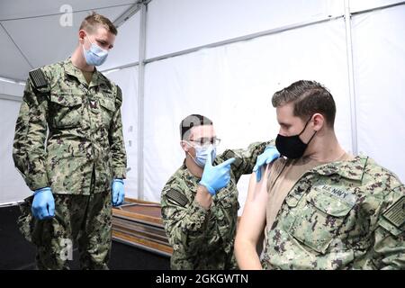 US Navy Petty Officer 2. Klasse Adam White, links, ein gebürtiger aus Elgin, Texas, zugewiesen zur Naval Air Station Corpus Christi, beobachtet als Seaman Apprentice Angel Ontiveros, ein gebürtiger Wheeler, Texas, zugewiesen an Navy Medicine Readiness and Training Command Jacksonville, Bewegungen eine Impfadministration an US Navy Petty Officer 2. Klasse Robert O’Bryant, rechts, ein Louisville, Kentucky, gebürtiger zugewiesen zu Navy Medicine Readiness and Training Command Jacksonville während der Ausbildung im Community Impfzentrum in Gateway Mall in Jacksonville, Florida, Freitag, 30. April 2021. USA N Stockfoto