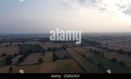 Ein Blick aus der Luft über die flachen Felder und Weiden in den Dunst vor uns, mit Sonnenuntergang im Westen. Stockfoto