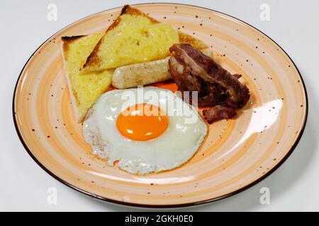 Englisches Break-fast-Konzept, Spiegelei mit sonniger Seite, Käsepoast, knusprigem Speck und Wurst Stockfoto