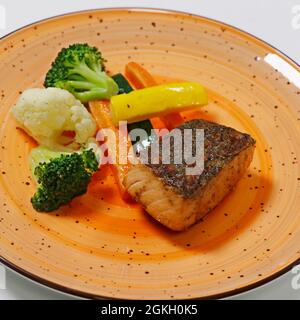 Gegrillter Lachsfisch mit gedämpftem Gemüse, einschließlich Karotten, Blumenkohl, Brokkoli und Zucchini, gesundes Lebensmittelkonzept Stockfoto