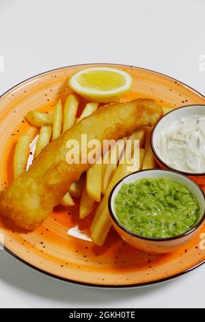 Fisch und Chips mit Tartarsauce, matschigen Erbsen und Pommes frites Stockfoto