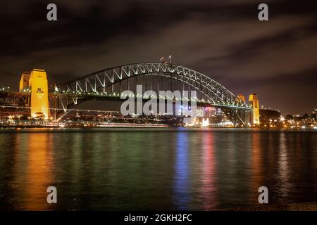 Blick auf den Hafen von Sydney, Australien, bei Nacht, mit Hafenbrücke und Hafengebiet Stockfoto