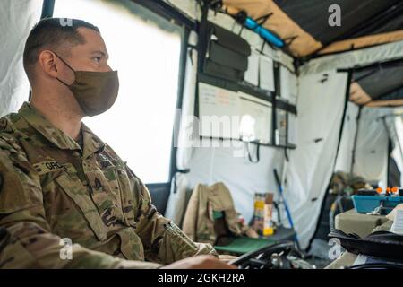 US Army Staff Sgt. Steven Gross, ein Gesundheitsbeaufseher des Hauptquartiers 204. Ingenieurbataillon, 153. Truppenkommando, 53. Truppenkommando, empfängt Patienten in der Hilfsstation an seinem Schreibtisch im Regional Support Camp Panther, North Vernon, Ind., 20. April 2021. Soldaten der Nationalgarde von NY unterstützen andere Bataillone der Nationalgarde während der Guardian Response Übung 21 in Indiana operativ und logistisch. Stockfoto