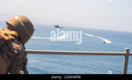 PACIFIC OCEAN (20. April 2021) Eine US Marine with Weapons Company, Battalion Landing Team 1/1, 11. Marine Expeditionary Unit, beobachtet, wie eine AH-1Z Viper, die dem Marine Medium Tiltrotor Squadron (VMM) 165 (verstärkt), 11. MEU, zugewiesen ist, kleine Boote von Bord des Amphibiendocks USS Pearl Harbor (LSD 52) abfängt, April 20. Die Marineinfanteristen und Matrosen der 11. MEU führen Routinetraining als Teil der Essex Amphibious Ready Group (ARG) durch. Zusammen werden das 11. MEU, das amphibische Squadron (PHIBRON) 1 und Schiffe als ARG bezeichnet. Stockfoto