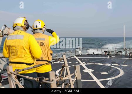 ENGLISCHER KANAL (21. April 2021) Boatswain's Mate 2nd Class Cody Johannes, Mitte, Und Boatswains Mate 1st Class Tecara Grey, links, simulieren die Landung eines behinderten Flugzeugs, gespielt von John Wilson-Rudd, Chief Petty Officer der Royal Navy, Aviation Air Engineer 3 für Flag Officer Sea Training (FOST), auf dem Flugdeck des Arleigh Burke-Klasse-Lenkflugzeugzerstörers USS Ross (DDG 71), 21. April 2021. FOST ist eine dreiwöchige Übung, die von der Royal Navy geleitet wird und die Kampffähigkeit des Schiffes testet. Ross, der nach Rota, Spanien, weitereingesetzt wurde, ist im Einsatzgebiet der Sechsten US-Flotte zur Unterstützung von o auf Patrouille Stockfoto