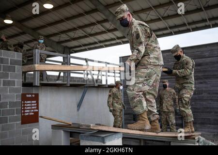 Soldaten der US-Armee mit dem Army Reserve Sustainment Command balancieren auf einer Holzplanke, während sie einen Holzbalken auf eine Plattform während eines Leadership Reaction Course auf Camp Bullis in San Antonio, Texas, 21. April 2021, bewegen. Der Kurs „Führungsreaktion“ ist Teil der Contracting Operational Readiness Exercise-21, die Soldaten durch verschiedene Ereignisse wie die Qualifikation von Waffen, den Army Combat Fitness Test und andere zusätzliche Schulungen validiert. Stockfoto