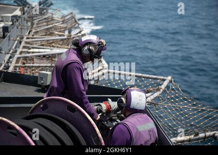 210421-N-WQ732-2070 ARABIAN GULF (21. April 2021) Gasturbinentechniker (mechanisch) 3. Klasse Madelyn Baltazar, links, und Maschinist's Mate 2. Klasse Devin Reeves verstauen während des Flugbetriebs im Arabischen Golf am 21. April eine Kraftstoffleitung auf dem Flugdeck des Lenkraketen-Kreuzers USS Monterey (CG 61). Monterey unterstützt die IKE Carrier Strike Group, während sie im 5. Flottengebiet der USA eingesetzt wird und Marinestützungen durchführt, um die maritime Stabilität und Sicherheit in der Zentralregion zu gewährleisten, wobei das Mittelmeer und der Pazifik durch den westlichen Indischen Ozean und drei strategische Chok miteinander verbunden werden Stockfoto