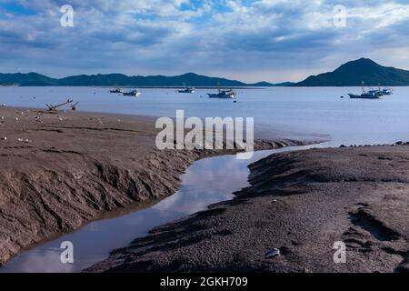 Wunderschöne Spiegelungen von Wattflächen an der Küste. Landschaft von Fischerbooten, die im Meer schwimmen. Ganghwado Island, Incheon, Südkorea. Stockfoto