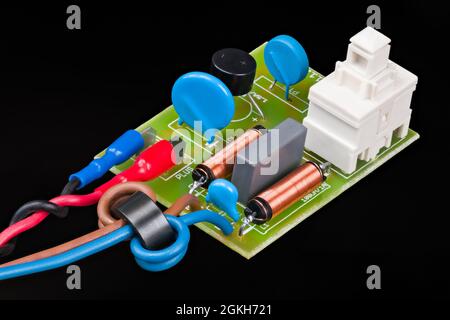 Elektronische Komponenten des Stromversorgungsmoduls für Elektromotoren auf schwarzem Hintergrund. Ferritperlen, Induktivitäten, Keramikfilter-Kondensatoren oder ein-aus-Schalter auf der Leiterplatte. Stockfoto