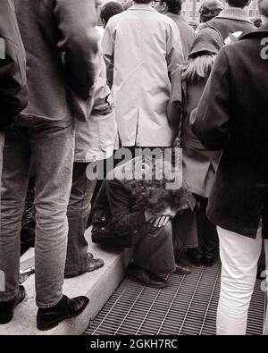 EIN JUNGER MANN AUS DEN 1960ER-JAHREN, DER AUF EINEM BORDSTEINKOPF IN SEINEM SCHOSS INMITTEN DER MENSCHENMENGE SITZT - C11051 HAR001 HARS-KOPIE RAUM IN VOLLER LÄNGE MASSE PERSONEN MÄNNER RISKIEREN NERVÖSE KRANKHEIT BEUNRUHIGT B & W BESORGT SAMMELN TRAURIGKEIT RUNDE ANGST LEIDEN HOHEN WINKEL SEINE VERZWEIFLUNG DEMONSTRATION STIMMUNG POLITIK PSYCHISCHE GESUNDHEIT DUNSTIG SEPARATE EINDÄMMUNG BENACHTEILIGT SCHLECHTE GESUNDHEIT SPANNUNGEN UNZUFRIEDEN ENTTÄUSCHT GETRENNT VERARMTE INMITTEN MISERABLE GEDRÄNGE JUNGE ERWACHSENE MANN JUNGE ERWACHSENE FRAU SCHWARZ UND WEISS VERSTÖRT HAR001 INDIVIDUELLE PSYCHISCHE ERKRANKUNG ALTMODISCH Stockfoto