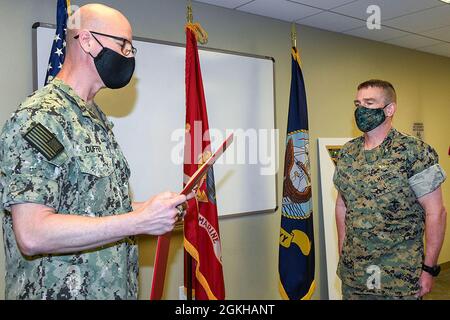 210422-N-DG679-039 JACKSONVILLE, Florida (22. April 2021) Col. Fred Schenk hört zu, als sein Zitat zum Ende der Tour von Capt. Grady Duffey während einer Befehlswechselzeremonie im Naval Air Station Jacksonville gelesen wird. Schenk wurde die Legion of Merit für einen außergewöhnlich verdienstvollen Dienst bei der Leistung herausragender Leistungen als Kommandant der FRCSE verliehen. Stockfoto