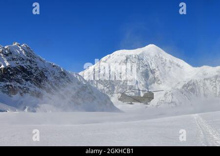 Ein CH-47F Chinook-Hubschrauber von B Company, 1. Bataillon, 52. Luftfahrtregiment wirft eine Schneewolke auf, als er auf dem Kahiltna-Gletscher landet, 22. April 2021. Flieger der Einheit, auch bekannt als die Zuckerbären, reisten von Fort Wainwright an, um dem National Park Service zu helfen, die notwendige Ausrüstung und Ausrüstung für das Basislager auf der 7,200-Fuß-Ebene des Kahiltna-Gletschers für die Klettersaison 2021 auf Denali zu besorgen, Der höchste Berg in Nordamerika. Der Berg hinter der Landung Chinook ist 17,400-Fuß-Mount Foraker. (Foto der Armee/John Pennell) Stockfoto