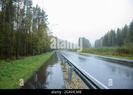 Ein Straßenabschnitt mit einem Fußgängerweg, der bei regnerischem Wetter entlang liegt Stockfoto