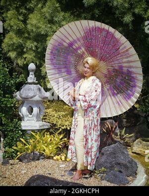 60S BLONDE FRAU BOUFFANT FRISUR UNTER GROSSEN ROSA BEMALTEN REGENSCHIRM SONNIGEN JAPANISCHEN GARTEN TRAGEN KIMONO BEDRUCKTE ROBE - KG3465 CYP001 HARS ROBE GROWNUP LUXUS IN VOLLER LÄNGE PERSONEN ERWACHSEN CHARAKTER SONNIG THEMA KIMONO BAMBUS FREIZEIT ORIENTALISCHE STILE GEMALT STILVOLLE ANONYME MODE FRISUR MENSCHEN ERWACHSENE JUNGE ERWACHSENE FRAU BOUFFANT KAUKASISCHE ETHNIE EXOTISCHE HANDGEMACHTE ALTMODISCH GEDRUCKT Stockfoto