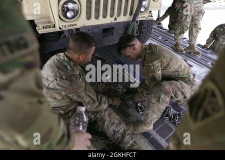 US Army Sgt. Kenny Ray, Bravo Battery, 1-181st Field Artillery Regiment, Task Force Iron Valor und Sgt. Trever Lacasse, Delta Company, 3-172nd Infantry – Mountain, TF Iron Valor, sichert während der Flugverladung auf der Ali Al Salem Air Base, Kuwait, 22. April 2021 einen Riemen. Die Soldaten der 1-181. FAR und D Co 3-172. Inf (mnt) bestehen aus TF Iron Valor. Stockfoto