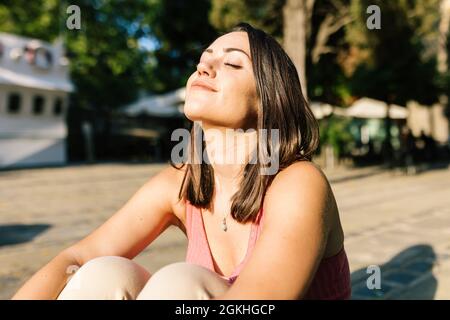 Junge Frau atmet tief frische Luft und meditiert, während sie auf dem Boden sitzt Stockfoto