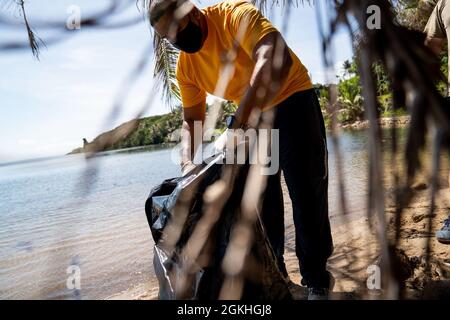 INALÅHAN, Guam (23. April 2021) LT. Cmdr. Andrew Regalado, Executive Officer bei Commander, Submarine Squadron 15, aus New York City, legt Müll in eine Tasche am Strand. CSS-15 und Naval Submarine Training Center Pacific, Detachment Guam, haben sich mit ihrem Schwesterdorf Inalåhan während einer Freiwilligenveranstaltung zum Thema Umweltfreundlichkeit zusammengeschlossen, um den Earth Day zu würdigen. Stockfoto