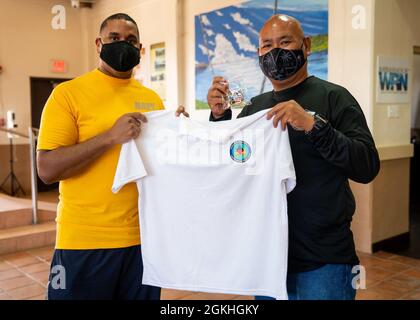 INALÅHAN, Guam (23. April 2021) LT. Cmdr. Andrew Regalado, Executive Officer bei Commander, Submarine Squadron 15, aus New York City, überreicht dem Bürgermeister von Inalåhan Anthony Chargualaf ein Geschenk, nachdem er Müll und Müll vom Strand entfernt hatte. CSS-15 und Naval Submarine Training Center Pacific, Detachment Guam, haben sich mit ihrem Schwesterdorf Inalåhan während einer Freiwilligenveranstaltung zum Thema Umweltfreundlichkeit zusammengeschlossen, um den Earth Day zu würdigen. Stockfoto