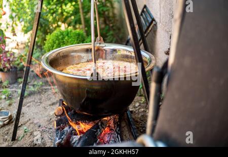 Topf mit Gemüsekessel über offenem Feuer, Zubereitung von Eintopf auf Holzgrill, Kochen im Freien Stockfoto