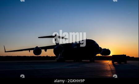 Die Sonne geht über einem C-17 Globemaster III Flugzeug auf der Fluglinie auf der Dover Air Force Base, Delaware, 23. April 2021 auf. Die C-17 Globemaster III ist das flexibelste Frachtflugzeug, das in die Luftwaffe einreisen kann. Das Flugzeug kann taktische Luftlift- und Fallenmissionen durchführen und während aeromedizinischer Evakuierungen Würfe von ambulanten Patienten transportieren. Stockfoto