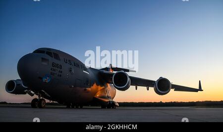 Die Sonne geht über einem C-17 Globemaster III Flugzeug auf der Fluglinie auf der Dover Air Force Base, Delaware, 23. April 2021 auf. Die C-17 Globemaster III ist das flexibelste Frachtflugzeug, das in die Luftwaffe einreisen kann. Das Flugzeug kann taktische Luftlift- und Fallenmissionen durchführen und während aeromedizinischer Evakuierungen Würfe von ambulanten Patienten transportieren. Stockfoto