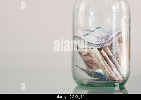 Geld, kolumbianische Banknoten im Glas, auf Glastisch, finanziell, Ersparnisse. Geldkassette, Glas voller Bargeld, Konzept der Einsparung von Geld, Planung und Kontro Stockfoto