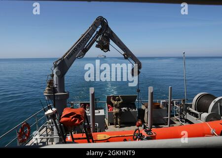 U.S. Army Sailor von der 109th Transportation Co., 259th Transportation Bn., arbeitet auf dem Deck des U.S. Army Logistics Support Vessel MG Charles P. Gross mit der USNS Bob Hope im Hintergrund am 26. April 2021, nahe der Küste von Durres, Albanien. Während DER Joint Logistics Over-the-Shore-Operationen DEFENDER-Europe 21 werden die Armee und die Marine zusammen mit multinationalen Partnern und Verbündeten daran arbeiten, die Fähigkeit der US-Armee zu demonstrieren, Truppen, Lieferungen und Ausrüstung schnell und überall auf der Welt als Reaktion auf die Krise zu liefern. Stockfoto