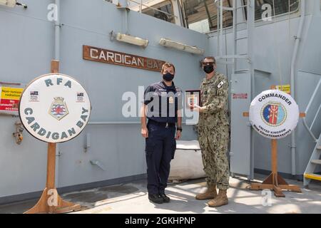 210426-AUN662-1194 ARABISCHER GOLF (26. April 2021) – Royal Navy Cmdr. Jim Lovell, Kommandant von Mine Warfare Battlestaff Red, links, überreicht ein Geschenk an den hinteren ADM. Curt Renshaw, stellvertretender Kommandeur des US Naval Forces Central Command und der US 5th Fleet, an Bord des Royal Fleet Auxiliary Landeschiffes Dock RFA Cardigan Bay (L 3009) nach einem Minengegenmaßnahmen-Fähigkeitsbericht während der Übung Artemis Trident 21 im Arabischen Golf, April 26. Artemis Trident 21 ist eine multilaterale Minenabhilfemaßnahmen zwischen Großbritannien, Australien, Frankreich und den USA, die auf die Verbesserung der gegenseitigen Interoperabilität und der Capabiliti ausgerichtet sind Stockfoto