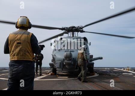 210426-N-HG846-0010 PAZIFISCHER OZEAN (26. April 2021) – Seeleute steigen am 26. April von der MH-60R Seahawk aus, die dem Hubschrauber-Seestreik-Geschwader (HSM-51) an Bord des Lenkraketen-Zerstörers USS Rafael Peralta (DDG 115) der Arleigh Burke-Klasse zugewiesen wurde. Rafael Peralta ist der Task Force 71/Destroyer Squadron (DESRON) 15 zugeordnet, der größten vorwärtseingesetzten DESRON der Marine und der wichtigsten Surface Force der 7. US-Flotte. Stockfoto