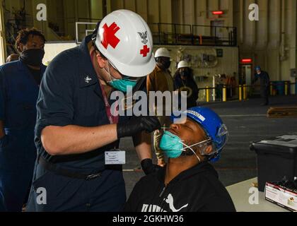 RIJEKA, Kroatien (Apr. 27, 2021) Hospital Corpsman 2nd Class Dillon Leggett, links, führt einen Nasenabstrich von Airman Emery Mahamery durch, um an Bord der Expeditionary Sea Base USS Hershel „Woody“ Williams (ESB 4) in Rijeka, Kroatien, am 27. April 2021 auf COVID-19 zu testen. Hershel „Woody“ Williams ist im geplanten Einsatzgebiet der Sechsten Flotte der USA zur Unterstützung der nationalen Interessen und der Sicherheit der USA in Europa und Afrika im Einsatz. Stockfoto