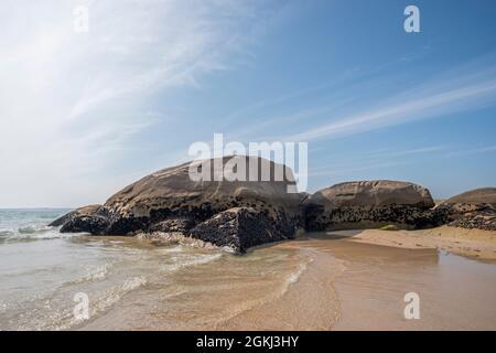 Große Granitfelsen am Ufer eines galizischen Strandes mit vielen Muscheln an der Oberfläche und Wasser- und Sandküssen in einem bukolischen Meeresportrait Stockfoto