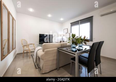 Esstisch aus schwarzem Glas mit Pflanzen und Wohnzimmer mit tv in der Ferienwohnung Stockfoto