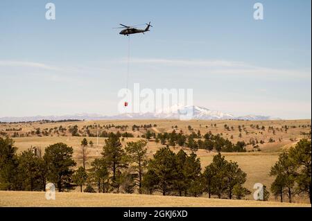 Ein UH-60 Blackhawk bereitet sich darauf vor, während eines vorgeschriebenen Verbrennungs- und Eimertropftrainings im North Training Area von Camp Guernsey am 29. April 2021 Wasser auf die Brandlinie zu Tropfen. Stockfoto