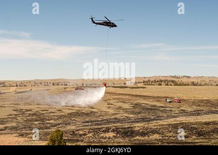 Ein UH-60 Blackhawk tropft während eines vorgeschriebenen Burn- und Eimer-Drop-Trainings am 29. April 2021 in Camp Guernseys North Training Area Wasser auf die Brandlinie. Stockfoto