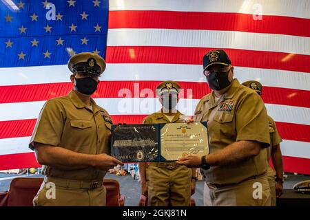 SASEBO, Japan (30. April 2021) Chief Electronics Technician Chris Colliver, links, erhält eine Auszeichnung der Marine von Capt. Kenneth ward, Kommandant des amphibischen Angriffsschiffes USS America (LHA 6), während Collivers Zeremonie zur Inbetriebnahme von Ensign in der Hangar Bay des Schiffes. Amerika, das führende Schiff der America Amphibious Ready Group, ist im Verantwortungsbereich der 7. Flotte der USA tätig, um die Interoperabilität mit Verbündeten und Partnern zu verbessern und als einsatzbereite Einsatztruppe für den Frieden und die Stabilität in der Region Indo-Pazifik zu dienen. Stockfoto