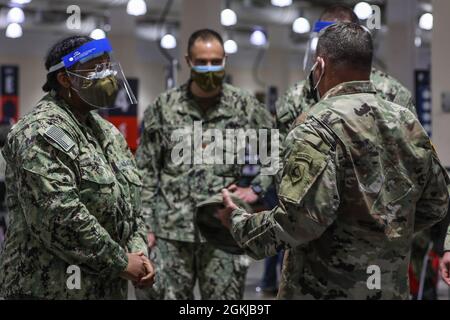 Der Hospitalist der US-Marine Kristie Julien, links, dem Naval Medical Center Portsmouth, Virginia, zugewiesen, erhält eine Münze von der US-Armee Brig. General Ronald Cupples, rechts, der stellvertretende Generaladjutant der Nationalgarde von Massachusetts, weil er vom 12. Bis 18. April der Vaccinator der Woche war und etwa 425 lokale Gemeindemitglieder impfen konnte, im Community Impfzentrum im Hynes Convention Center in Boston, 30. April 2021. US-Dienstmitglieder aus dem ganzen Land werden zur Unterstützung der Maßnahmen des Verteidigungsministeriums zur Reaktion auf Impfstoffe eingesetzt. US Northern Command, durch Stockfoto