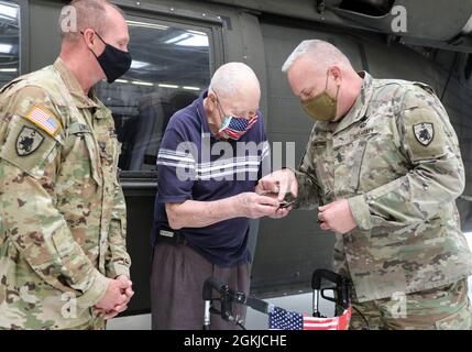 COL Gary Lewis, Kommandant der 63. TAB und Command Sgt. Maj. Paul Rezac, Senior Enlisted Advisor für die 63. REGISTERKARTE, präsentiert WWII-Veteran Paul Frederick mit einer 63. Registerkarte Münze und Patch in der Kentucky National Guard's Army Aviation Support Facility am 30. April 2021 in Frankfort Kentucky. Drei alteingesessene Bewohner, ein alteingesessener Freiwilliger und drei medizinische Mitarbeiter einer langfristigen Gesundheitseinrichtung in Lexington machten eine Führung durch den Hangar und checkten das Flugzeug und die Ausrüstung aus. Stockfoto