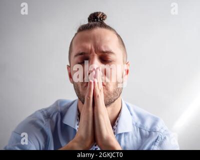 Weißer junger Hipster-Mann betet mit geschlossenen Augen Stockfoto