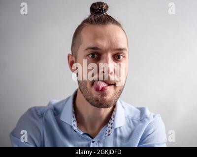 Der weiße junge Mann sieht lächerlich aus, wenn seine Zunge aus seinem Mund kommt Stockfoto