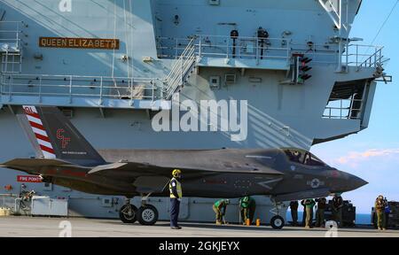 Eine Marine mit Marine Fighter Attack Squadron (VMFA) 211, Carrier Strike Group (CSG) 21 'The Wake Island Avengers' Taxi ein F-35B Joint Strike Fighter Lightning II an Bord von her Majesty's Ship (HMS) Queen Elizabeth auf See vor dem Vereinigten Königreich Stockfoto