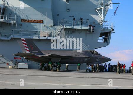 Eine Marine mit Marine Fighter Attack Squadron (VMFA) 211, Carrier Strike Group (CSG) 21 'The Wake Island Avengers' tachet einen F-35B Joint Strike Fighter Lightning II an Bord von her Majesty's Ship (HMS) Queen Elizabeth auf See vor der Küste des Vereinigten Königreichs Stockfoto