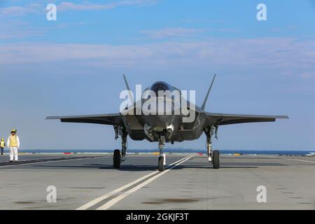 Eine Marine mit Marine Fighter Attack Squadron (VMFA) 211, Carrier Strike Group (CSG) 21 'The Wake Island Avengers' tachet einen F-35B Joint Strike Fighter Lightning II an Bord von her Majesty's Ship (HMS) Queen Elizabeth auf See vor dem Vereinigten Königreich Stockfoto