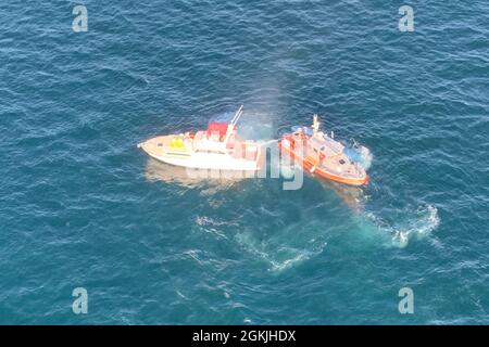 Küstenwache Hafenbesatzungsmitglieder an Bord eines 45-Fuß-Boot-Medium-Versuchs, am Dienstag, dem MaAY 4, ein Bootsfeuer mit einer Wasserpumpe zu löschen. Drei Menschen wurden gerettet, bevor das Feuer schließlich das 48-Fuß-Schiff zum Sinken brachte. Stockfoto