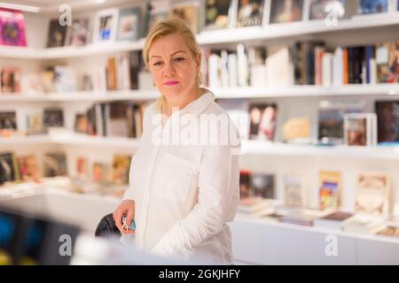 Porträt einer hübschen erwachsenen reifen Dame, die neue Bücher auswählt Stockfoto