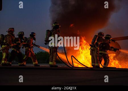 Feuerwehrleute, die der 7. Zivilingenieursmannschaft und der 512. CES zugewiesen sind, löschen während einer Feuerausbildung auf der Dyess Air Force Base, Texas, 4. Mai 2021, Flammen. Feuerwehrleute, die für die 7. Und 512. CES beauftragt wurden, führten die Live-Feuerausbildung mit Feuerwehrleuten des Flugzeugrettungsteams des Regionalflughafens Abilene durch, um die Sicherheit, die Kompetenz und die Interoperabilität zu verbessern. Stockfoto