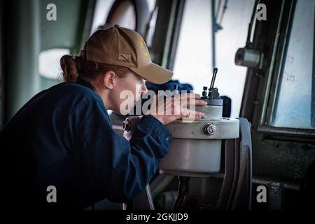 210504-N-NQ285-1064 ATLANTISCHER OZEAN (4. Mai 2021) Ensign Catherine Cohen, die dem Hafenlandschiff USS Carter Hall (LSD 50) der Harpers Ferry-Klasse zugewiesen wurde, überprüft die Haltung der italienischen Marine Carlo Bergamini-Klasse FREGATTE ANTONIO Marceglia (F 597) von der Brücke der Carter Hall während eines Formationstransits, 4. Mai 2021. Carter Hall ist im Atlantischen Ozean mit dem Amphibiengeschwader 4 und der 24. Marine Expeditionary Unit (24. MEU) als Teil der Iwo Jima Amphibious Ready Group tätig. Stockfoto