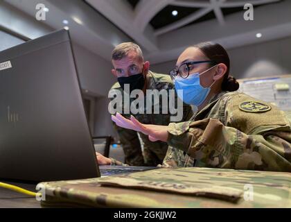US Army Reserve SPC. Kimberly Soto (rechts), eine Personalspezialistin bei der 338. Medizinischen Brigade, 3rd Medical Command Deployment Support, geht ihre persönlichen Bereitschaftsprozesse mit dem Kommandanten General Maj. General Joe Robinson, 3rd Medical Command Deployment Support, während der Übung Vibrant Response 21 der US Army North durch. Die diesjährige Übung hat die Task Force 76 und ihre Hauptquartiere durch eine Kommandoübung virtuell geschult und zertifiziert, die auf einem simulierten chemischen, biologischen, radiologischen und nuklearen Zwischenfall basiert. Stockfoto